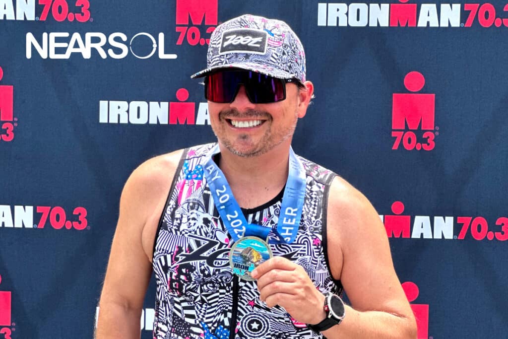 Victor Pereda holding the Iron Man 70.3 Tri Athlon Medal