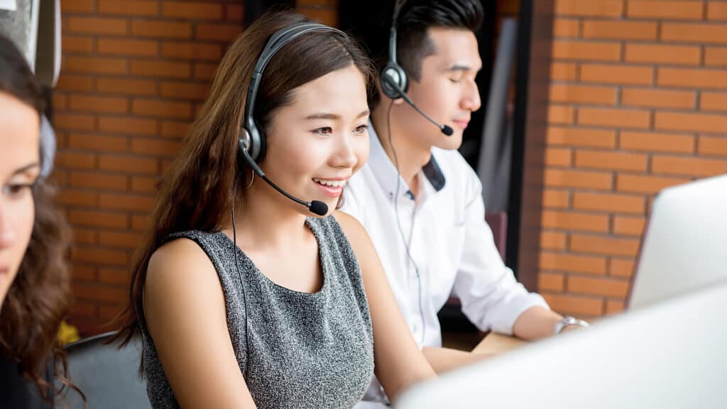 Smiling Asian businesswoman working in call center as an operator or telemarketer