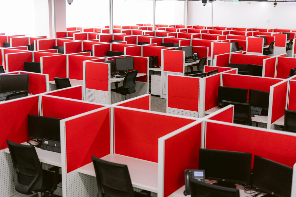 NEARSOL seat leasing office with rows of red-divided cubicles, each equipped with desks, chairs, and computer monitors