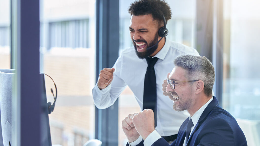 Two enthusiastic business professionals celebrating success in a modern office, symbolizing the impact of white label BPO solutions on scalable business growth.